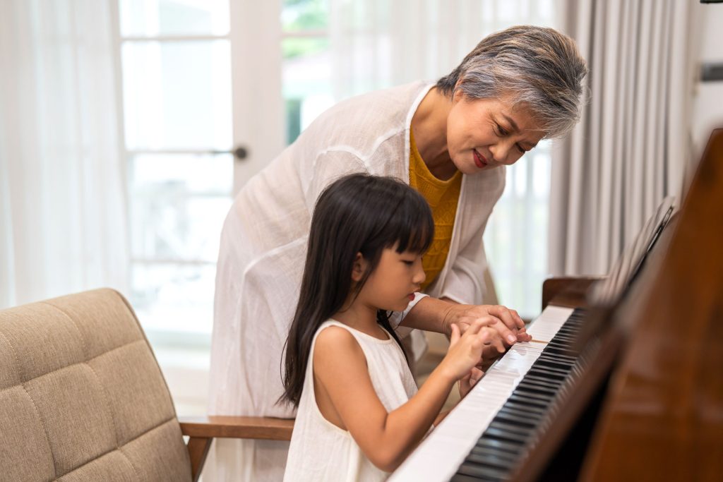 Playing Piano with Grandmother 1 An older woman shows a young child how to play the piano